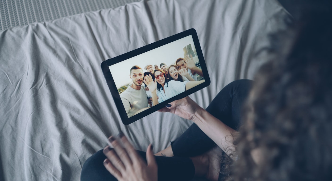 Una persona in videochiamata con un gruppo di amici sullo schermo del laptop.