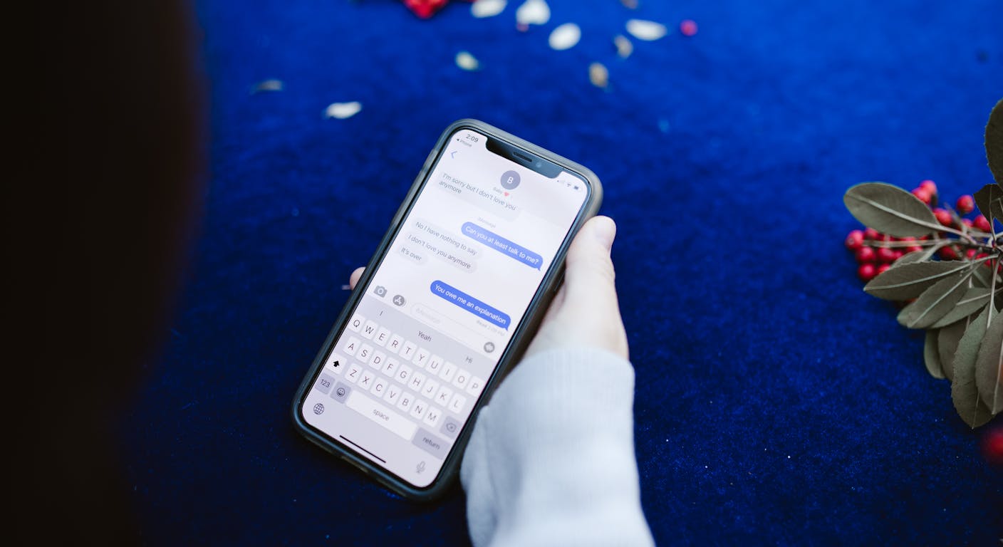 Una mano che tiene uno smartphone con una conversazione di chat sullo schermo.
