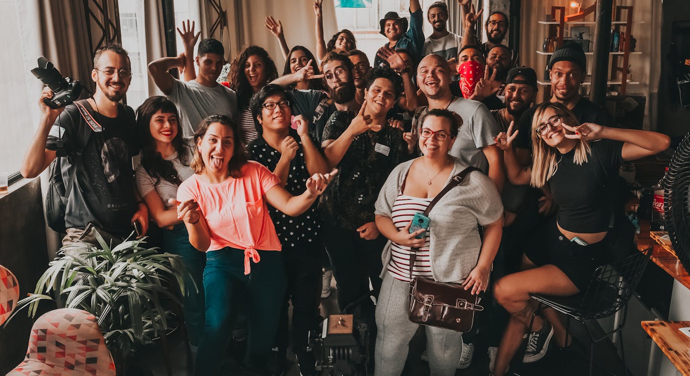 Un gruppo eterogeneo di persone che fanno facce allegre verso la fotocamera.